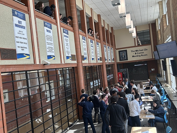 Students on a mock trading floor communicate with their teams to determine which stocks to buy and sell.