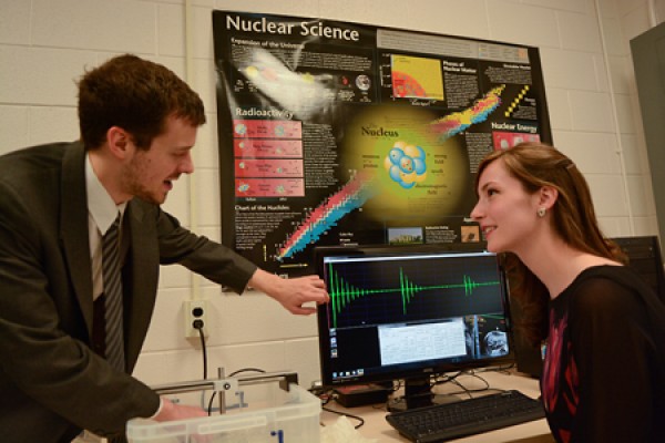 Andrew Ouellette demonstrates an experiment to Physics Club president Melissa Mather