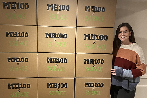 Education student Hope McMahon poses next to a stack of science kits.