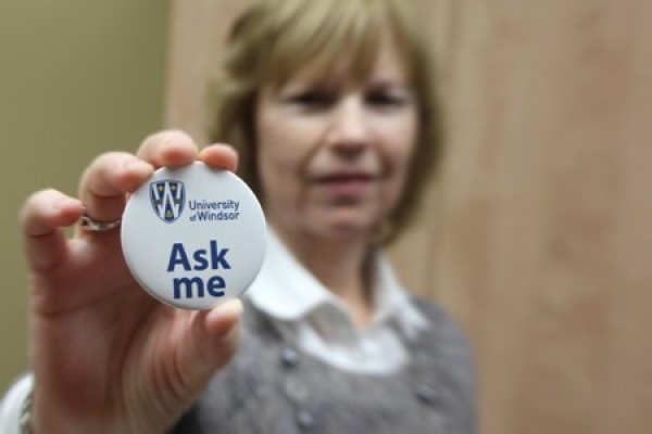 woman holding &quot;Ask Me&quot; button