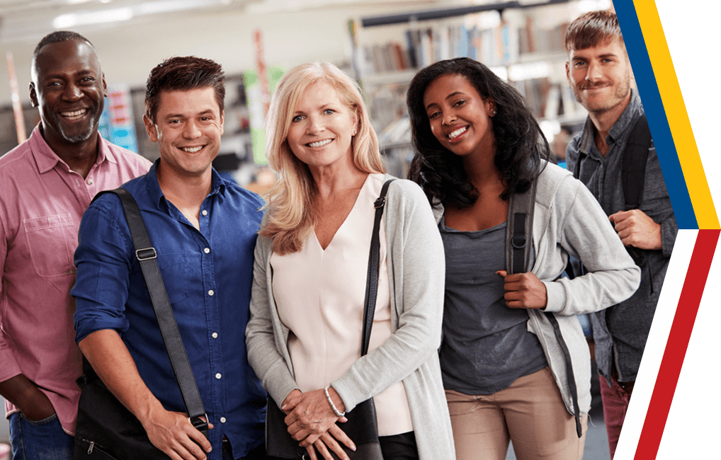 A group of mature students of various race standing in a library.