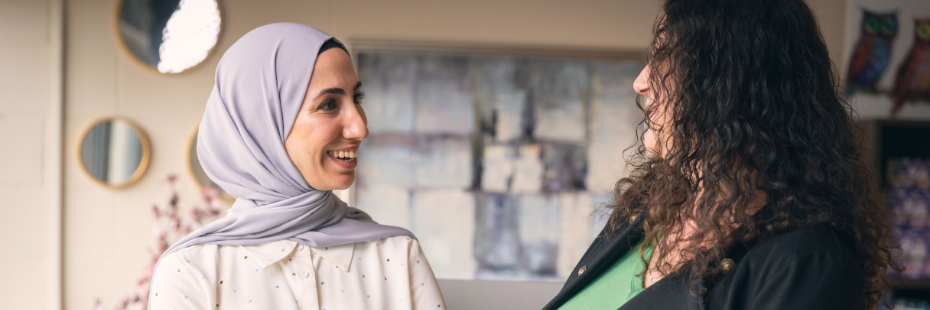 Two graduate students standing next to each other having a conversation