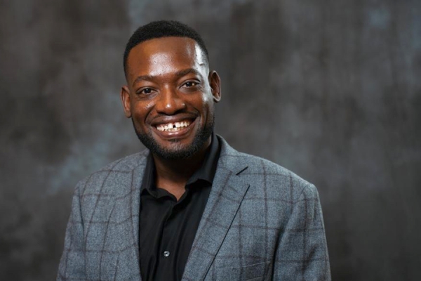 Headshot of Dr. Carlo Charles, a smiling Black man wearing a suit