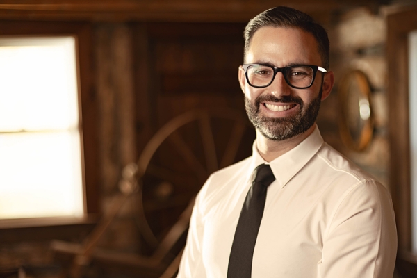 Headshot of a man in shirt and tie standing in the original cabin at Amherstburg Freedom Museum