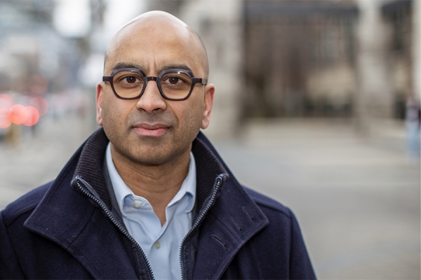 Headshot of a middle aged manwith a shaved head and wearing glasses