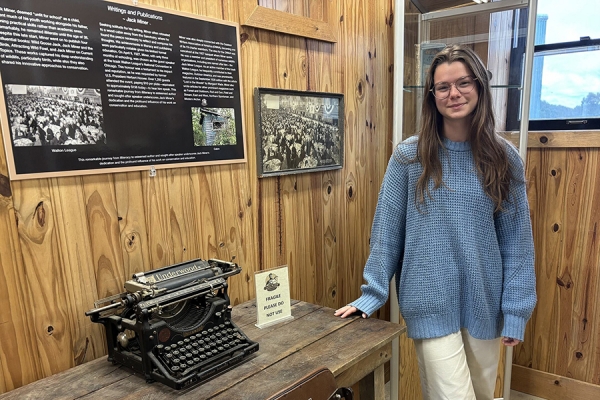 Woman with long brown hair, wearing a blue sweater stands in front of one of the exhibits in the Jack Miner Museum