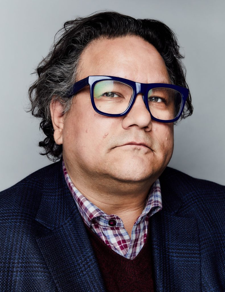 Headshot of an unsmiling Jesse Wente, a man with black hair with a bit of gray, wearing black rimmed glasses. 