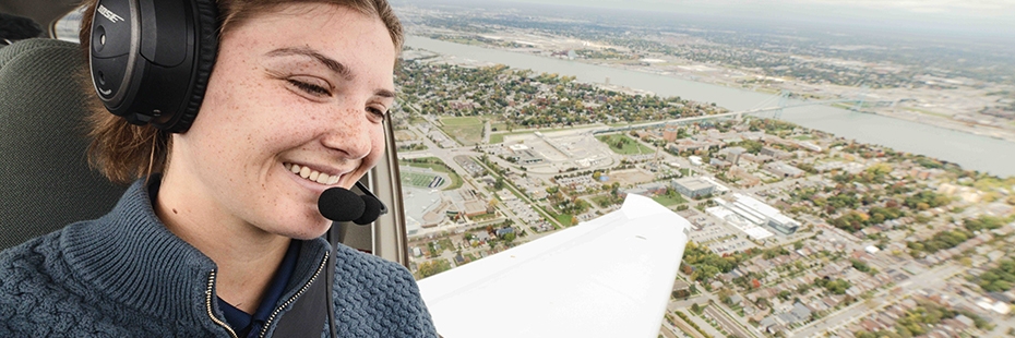 Paige Wakelin, a 2024 aviation grad,looking out cockpit window at UWindsor while piloting plane