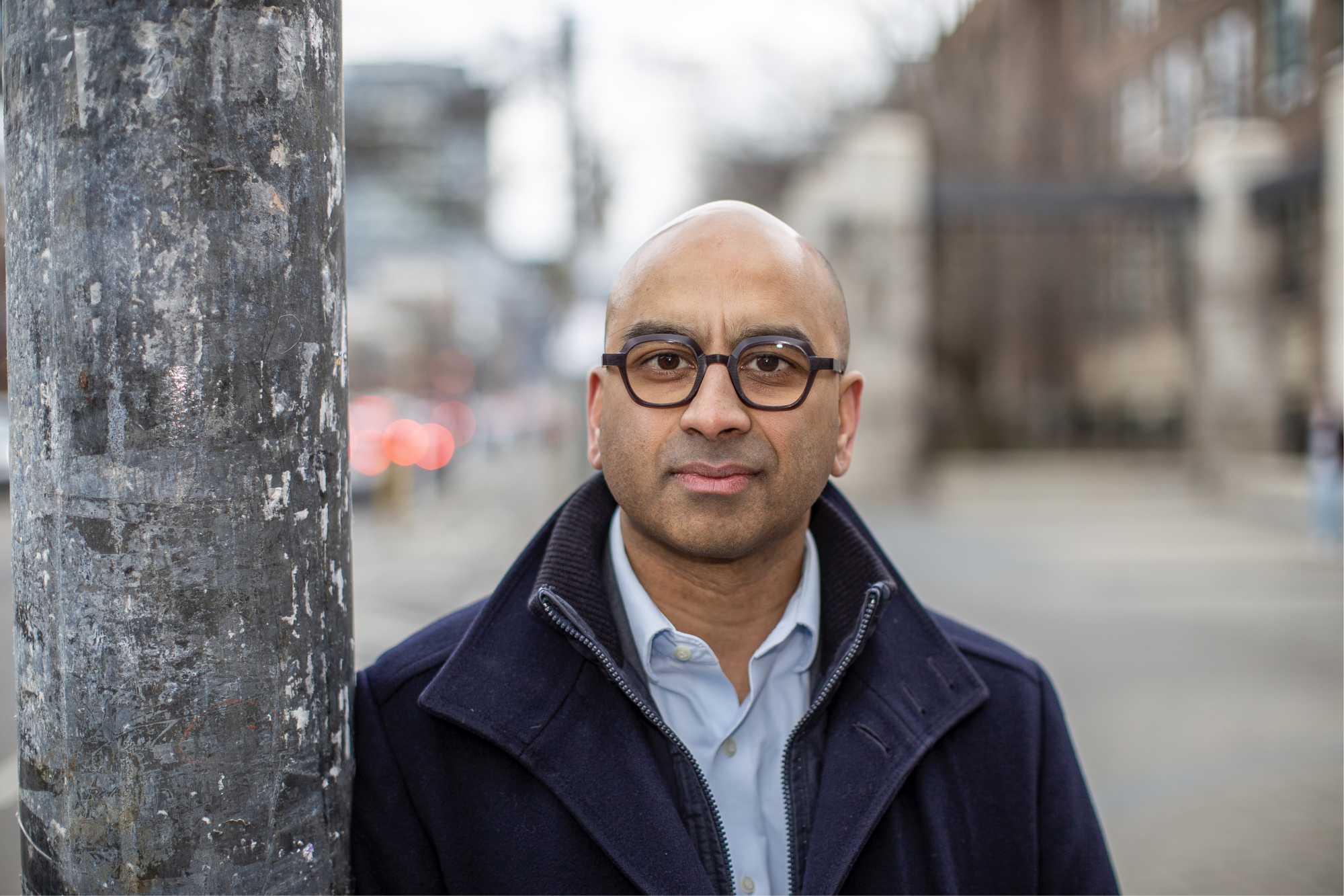 Man wearing glasses standing next to a tree