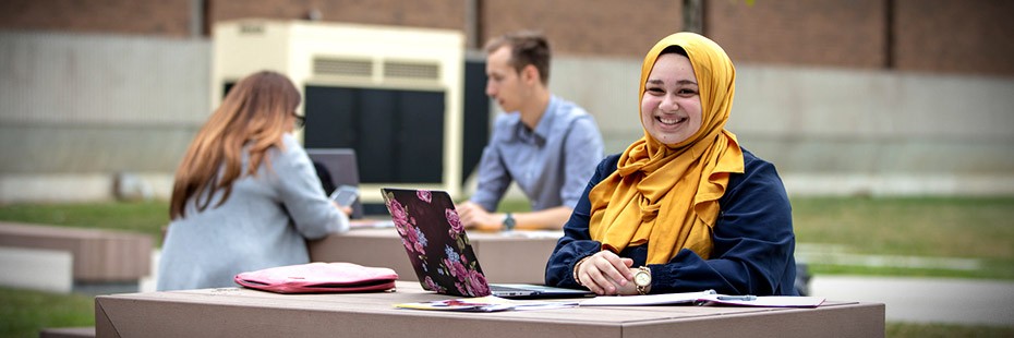 Student on laptop sitting outside at table