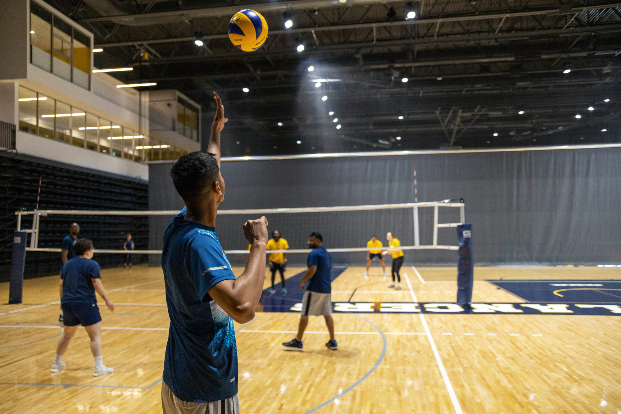 Student serves a volleyball in an intramural volleyball game