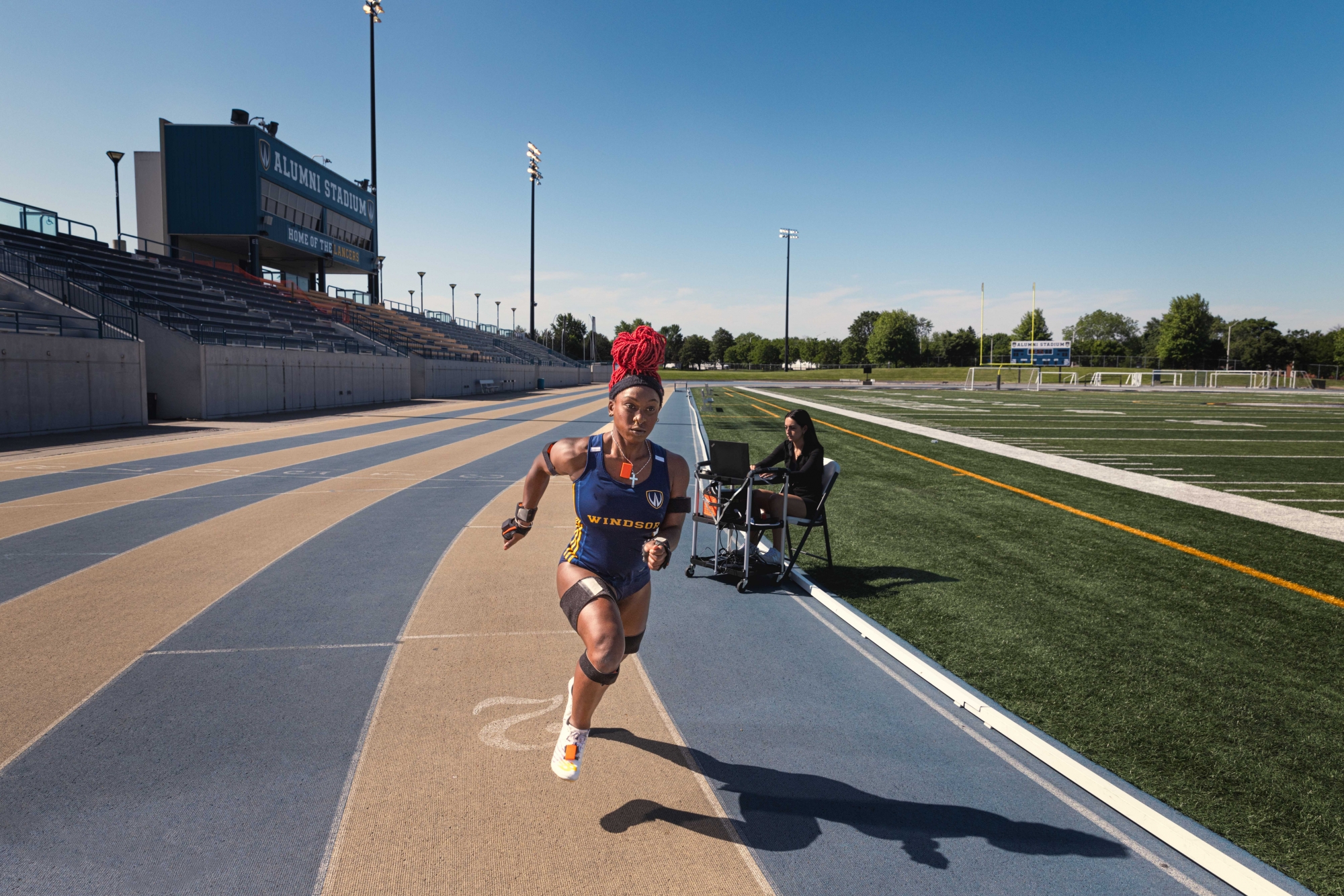 Track runner sprints in lane with researcher on laptop