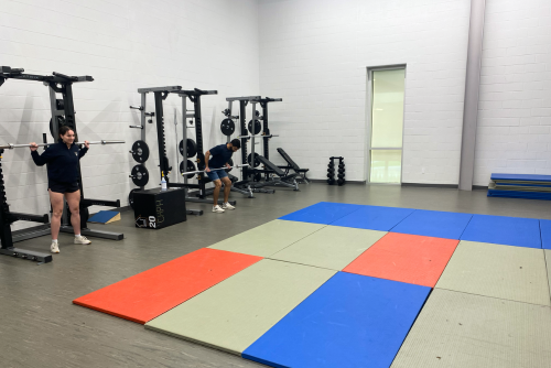 Two participants uses weights on squat rack