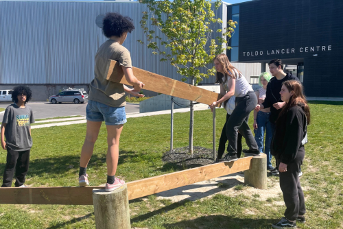 Participants hold board in challenge course.