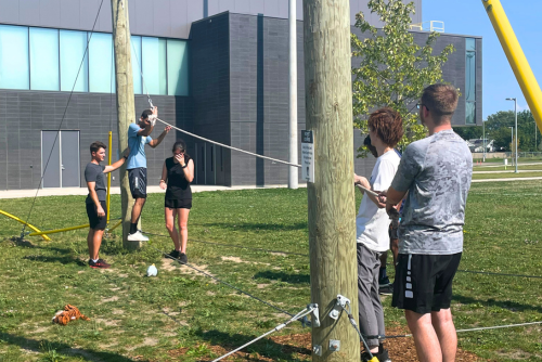 Participants balancing on a pole/rope on challenge course.