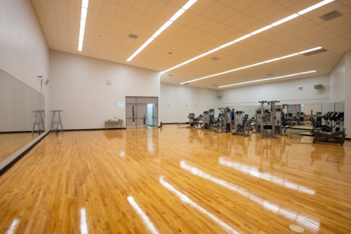 Large multipurpose room with hardwood and fitness equipment. 