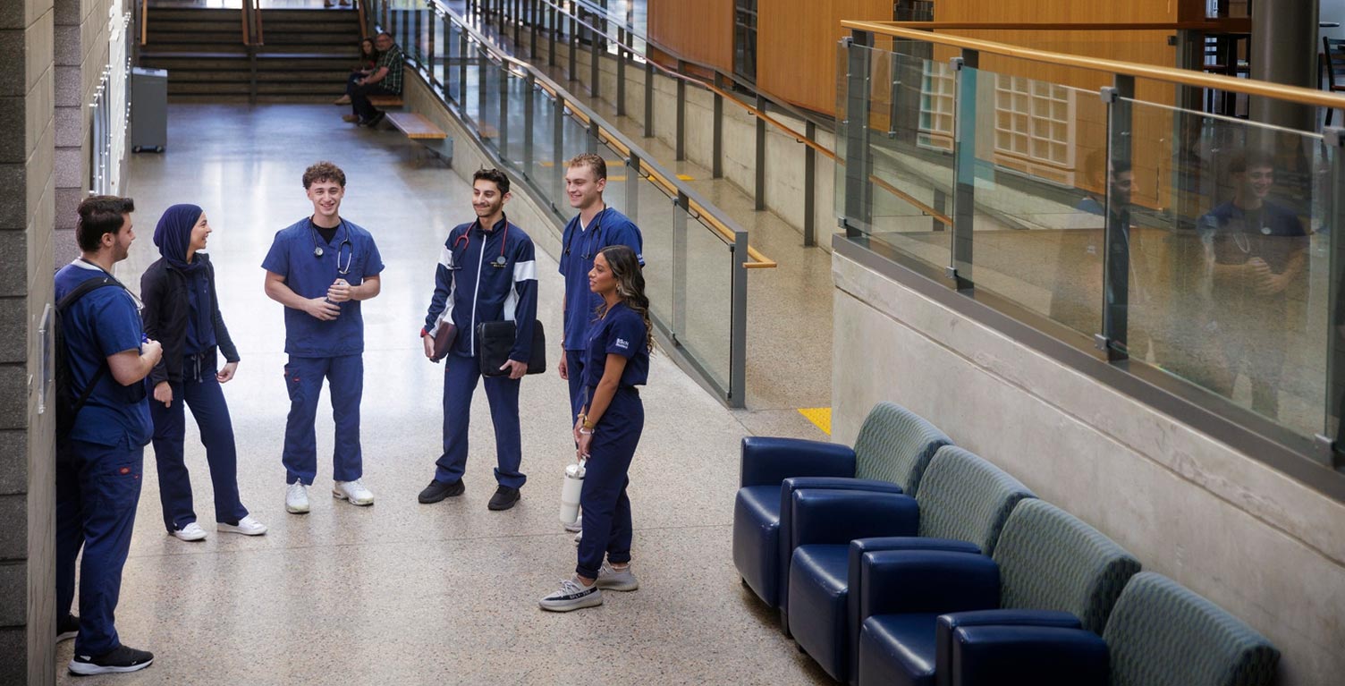 Group of Nursing student peer mentors standing in a hallway amidst discussion