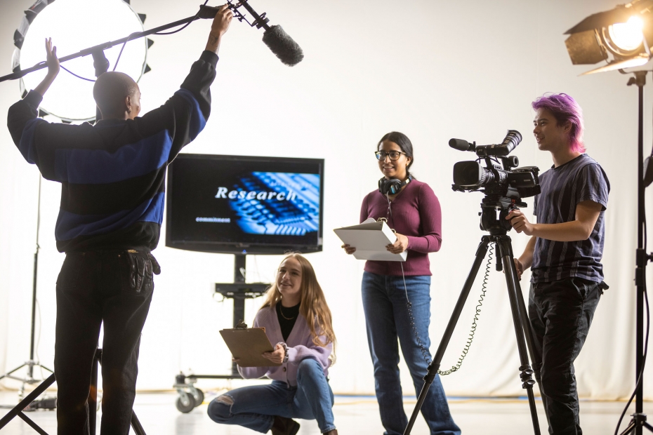 Four students work in various roles on a film production set