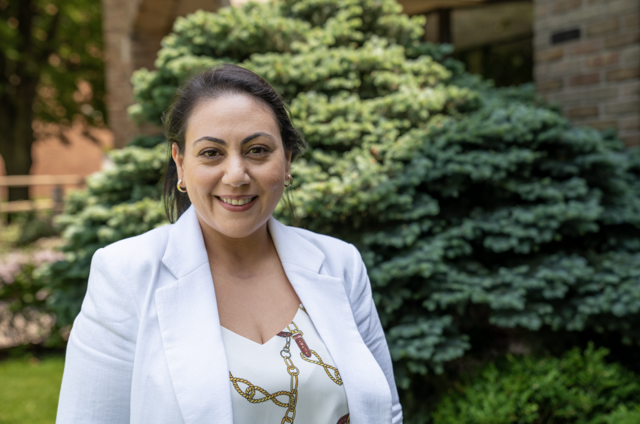 Marian Gayed smiles outside while wearing a white blazer and white shirt.