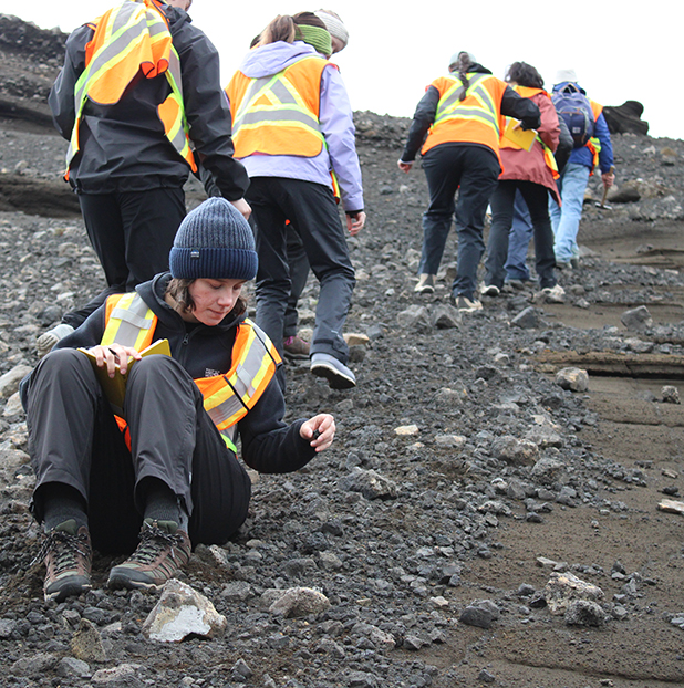 student crouching to investigate rocky soil