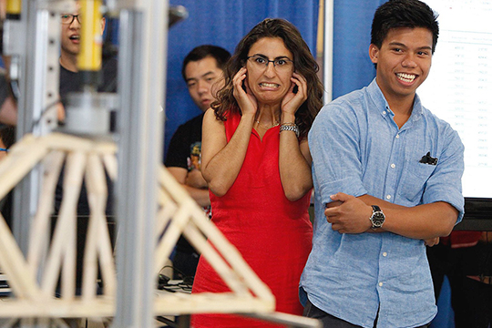 students watching their bridge model being tested