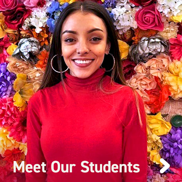 Closeup view of female student smiling in front of flower background