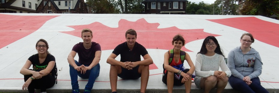 Incoming exchange students pose with the giant Canadian flag down at the Riverfront