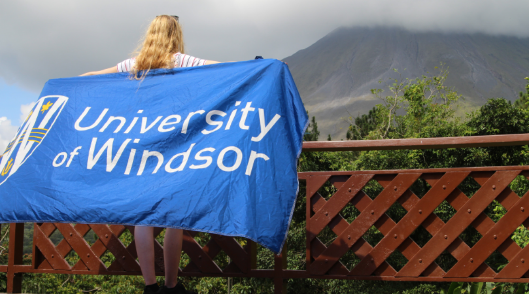 A student on exchange holding up the University of Windsor flag