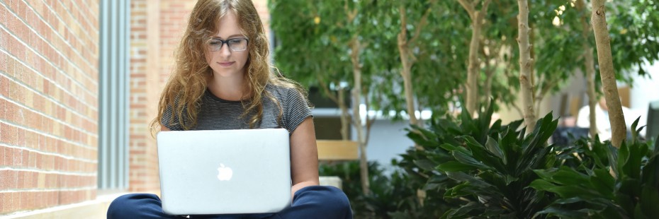 Student sitting on the floor, working on their laptop